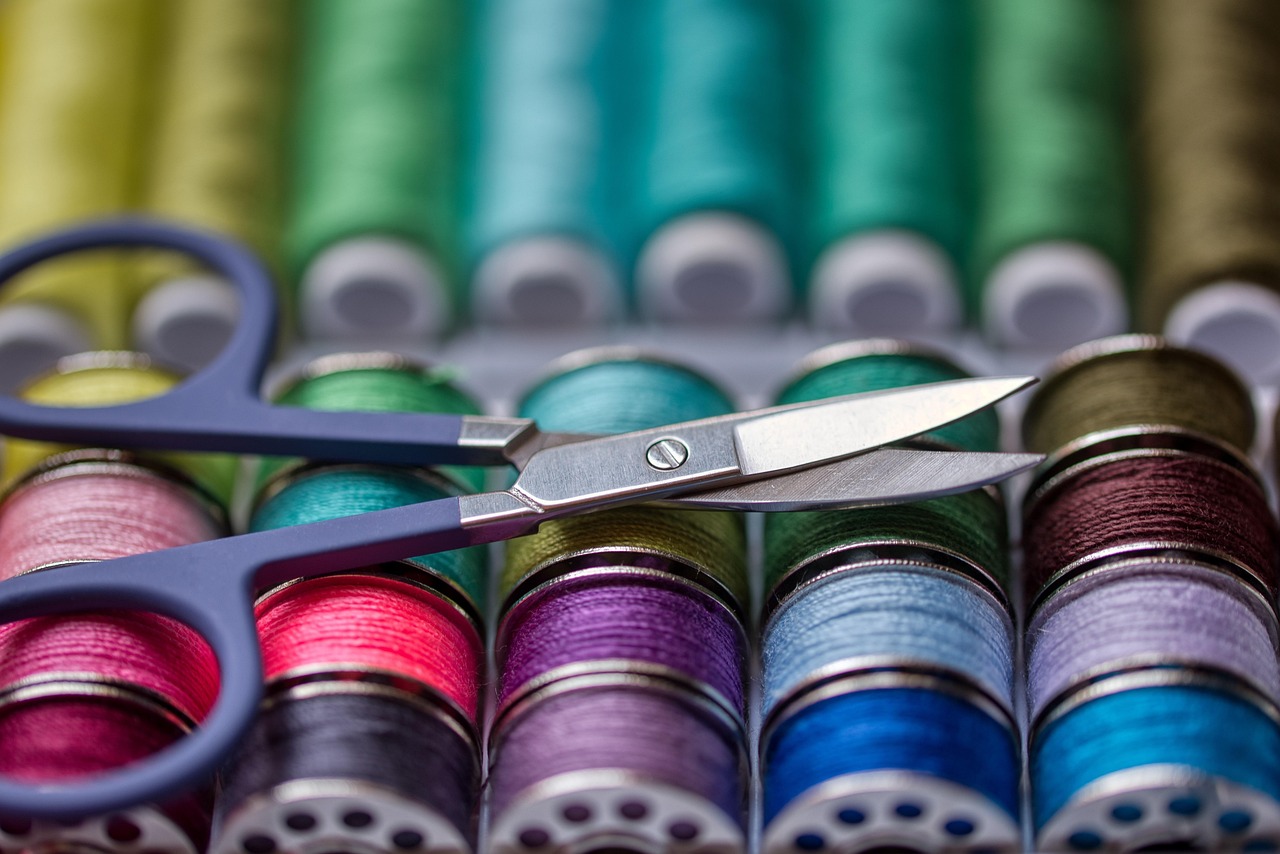 Thread, scissors, and a tape measure on a worktable.
