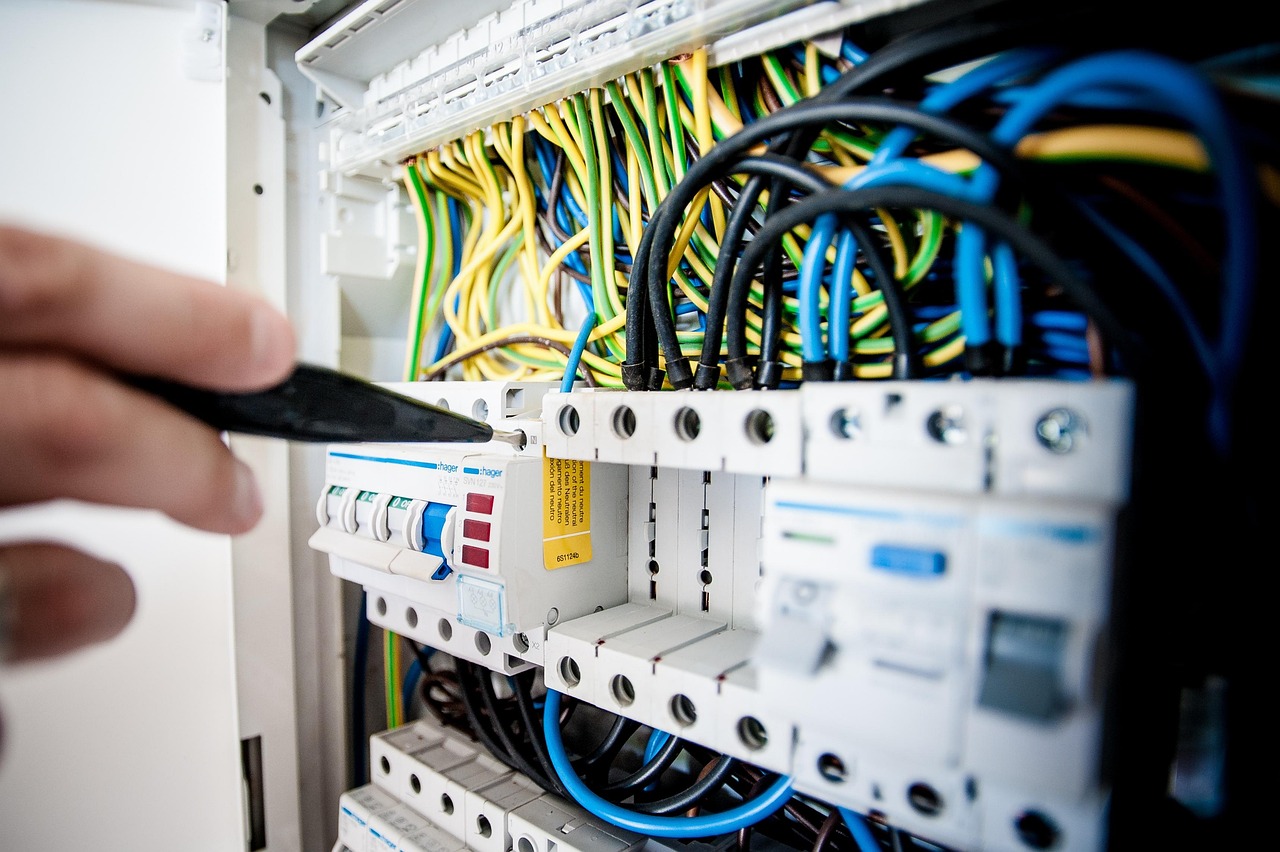 An electrician checking wiring at a consumer unit.